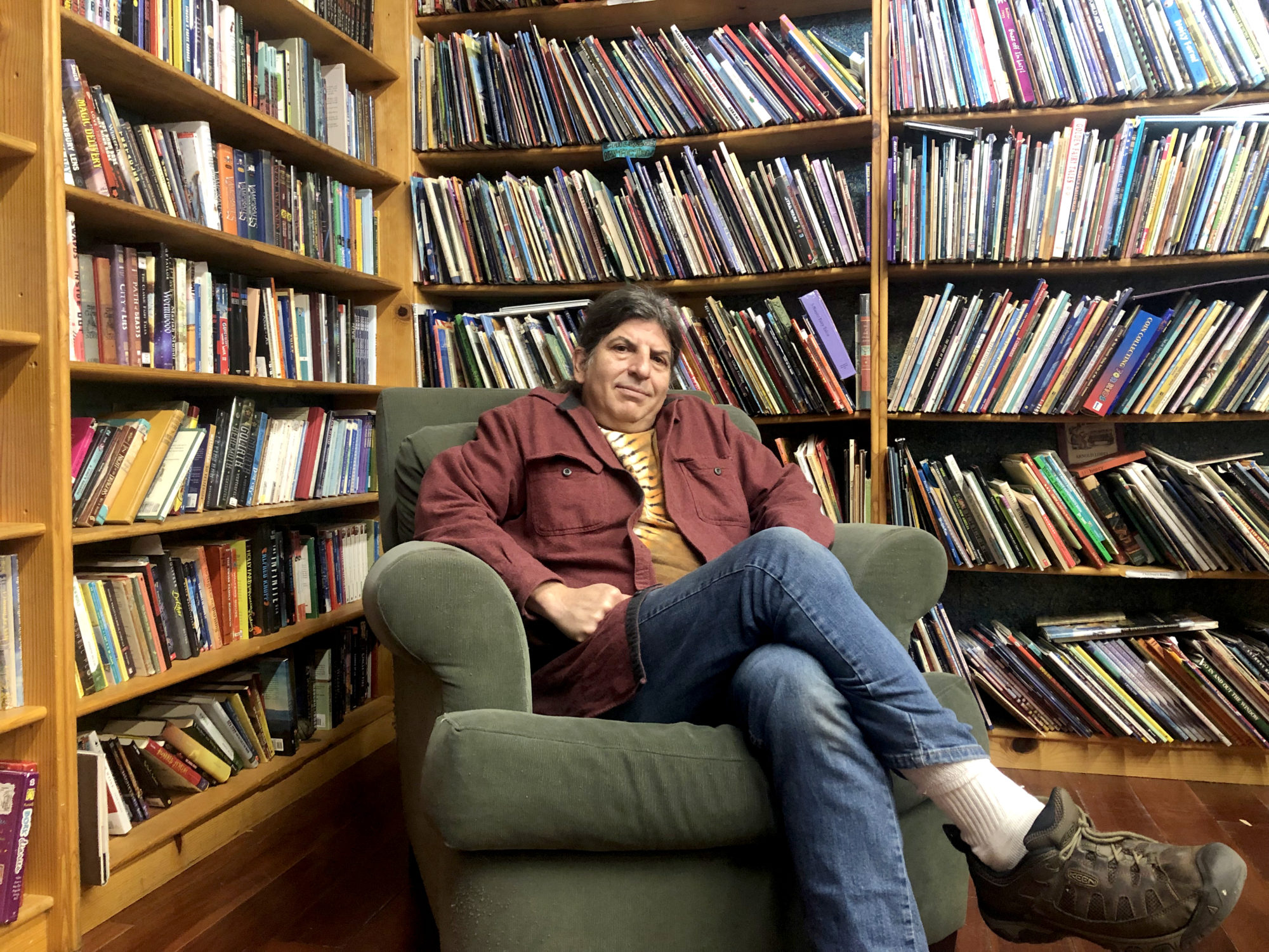 Dan Weinstein, owner of The Iliad Bookstore sits surrounded by books.