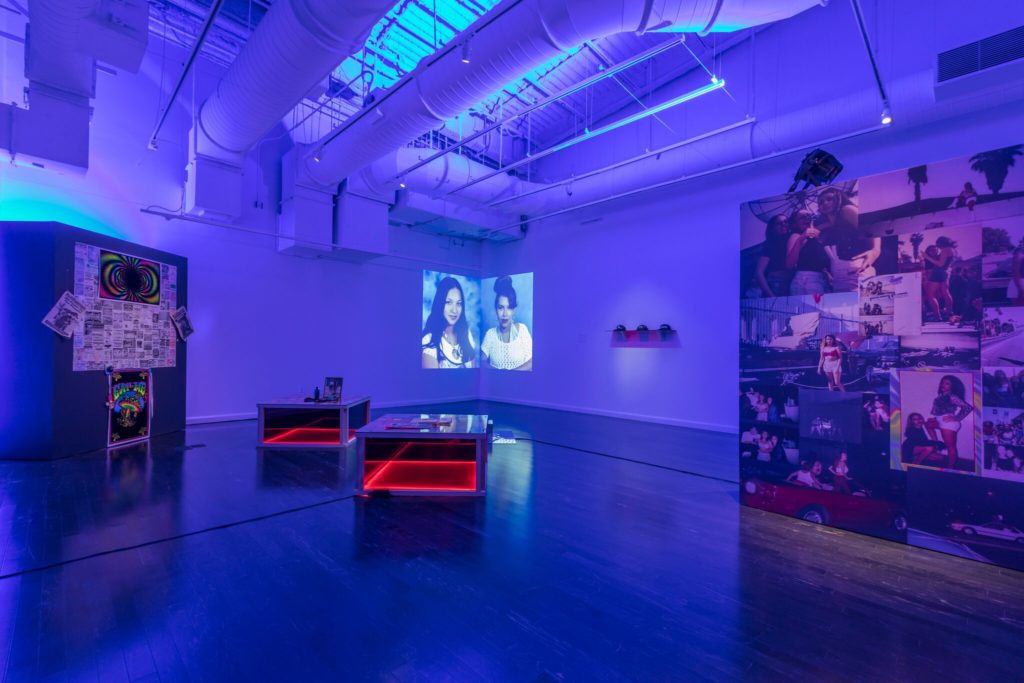 Photograph of gallery space featuring projected portraits and collages.