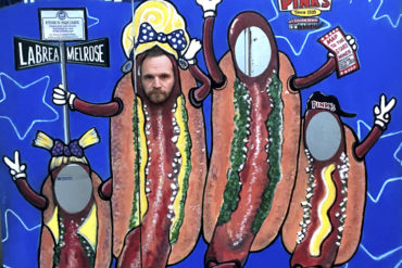 The writer posing for a photo in a Pink's Hot Dogs cardboard cutout