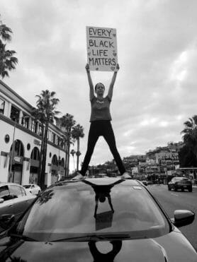 Protestor standing on top of a car.