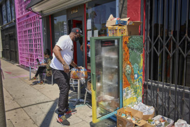 A man stocks the community refrigerator located outside Little Amsterdam Coffee.