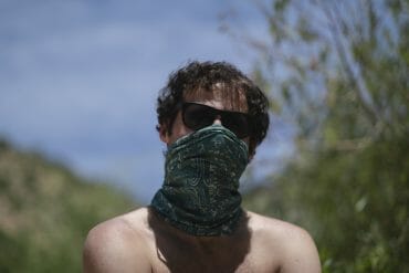 A hiker wearing a bandana over his face.