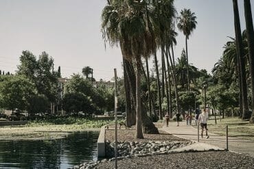 Pedestrians walk alongside Echo Park Lake while wearing protective face coverings.