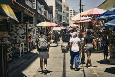 Masked shoppers walk through Santee Alley while following posted safety guidelines.