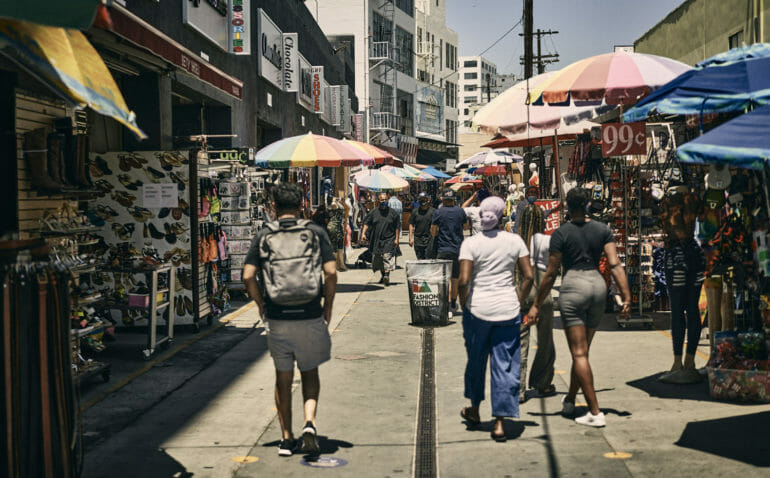 Masked shoppers walk through Santee Alley while following posted safety guidelines.