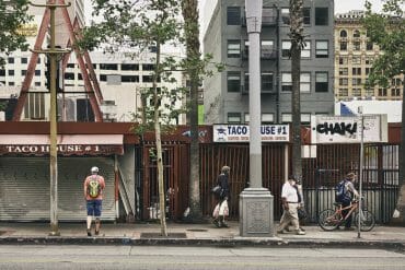 Pedestrians in downtown Los Angeles walk in front of closed storefronts.