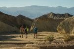 Three hikers travel on the Badlands Loop in Death Valley National Park.