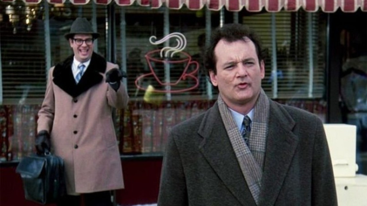 Two men in winter coats stand outside a diner.